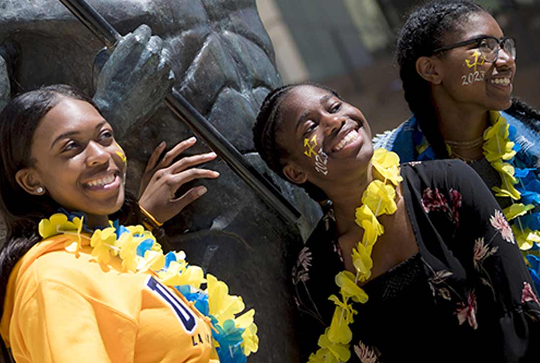 Three girls smiling by the Triton statue