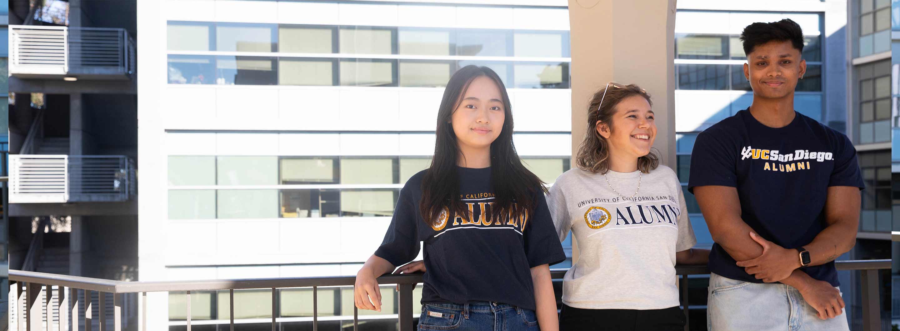 Two alumna and one alumnus wearing UC San Diego Alumni sweaters